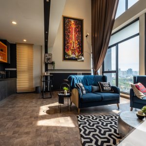 A modern, upscale living space in the Lavish Loft with plush seating, refined decor, and floor-to-ceiling windows showcasing a KLCC view.